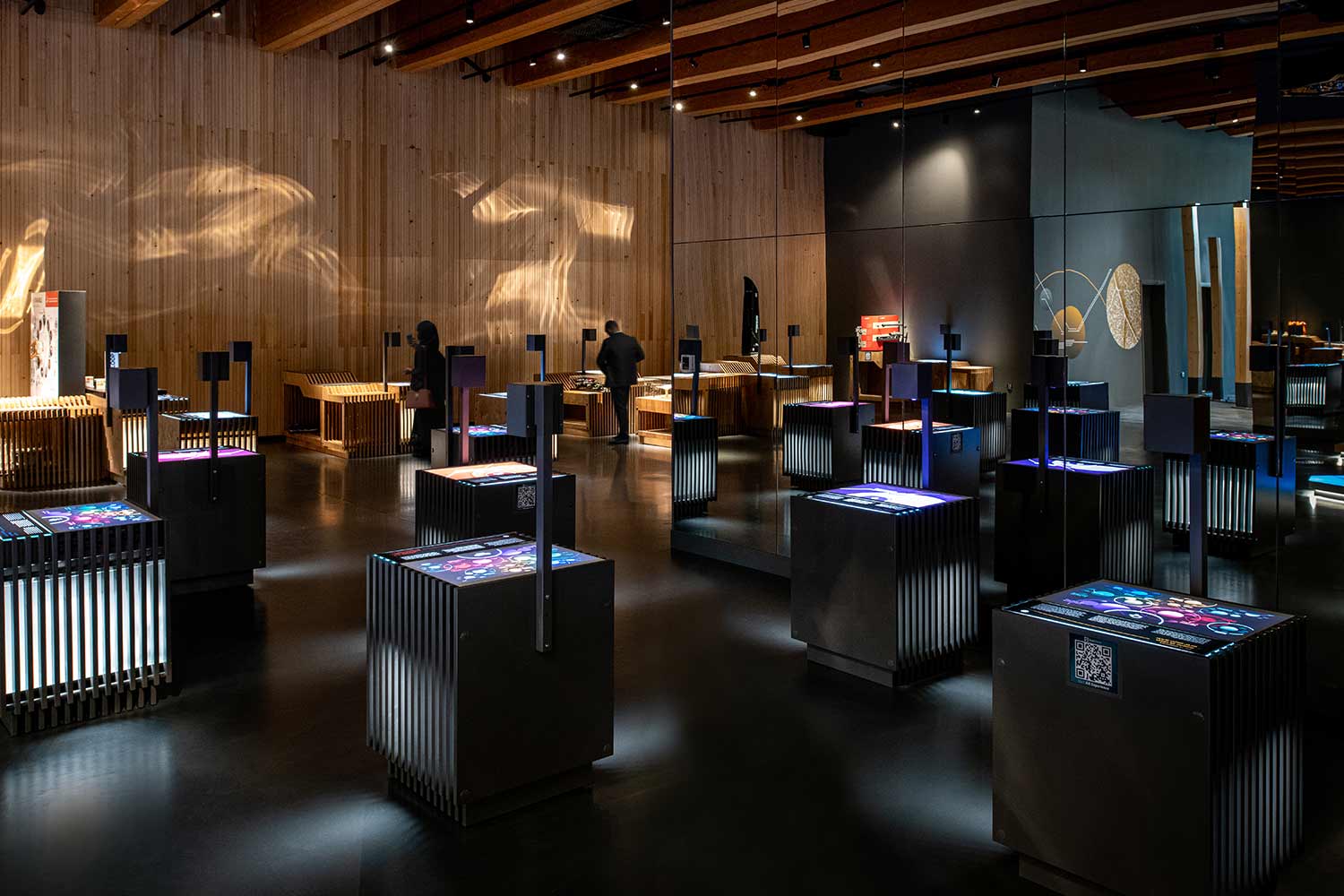 Dark room with illuminated display cases and people in the background